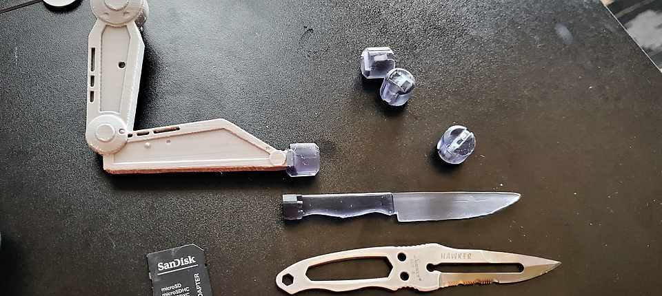 Several 3D-printed knife handle prototypes lined up on the workbench for a fit and grip test.