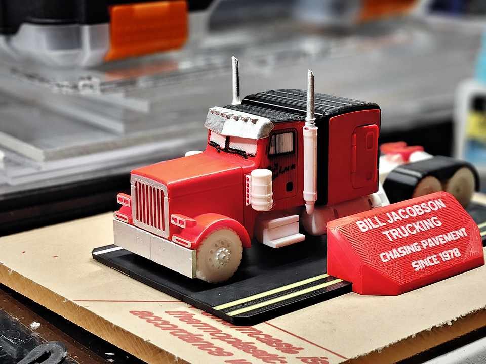 Commissioned red Peterbilt display model with 'Bill Jacobson Trucking' nameplates, finished on a wood stand.
