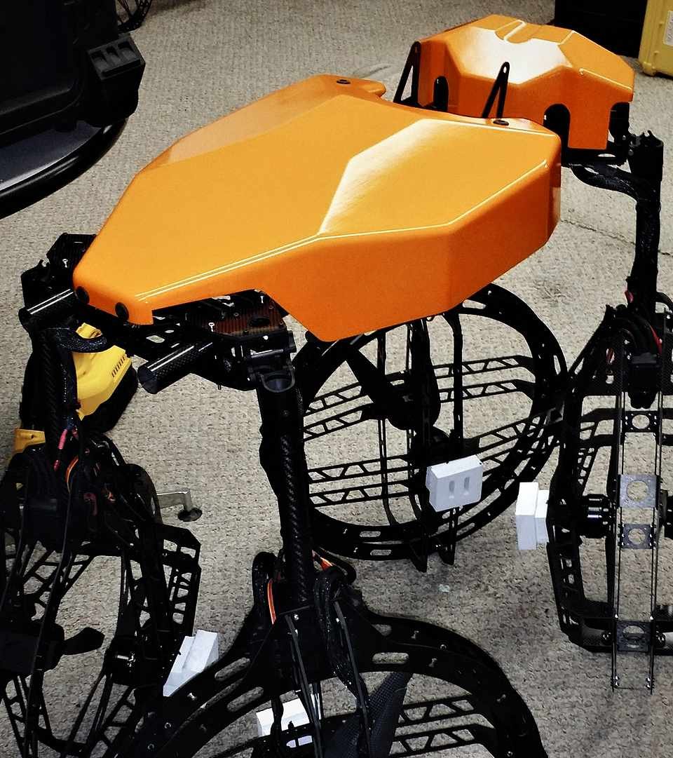 Close view of the orange quad-ducted hover platform's shrouded propeller and orange composite frame on the shop floor.