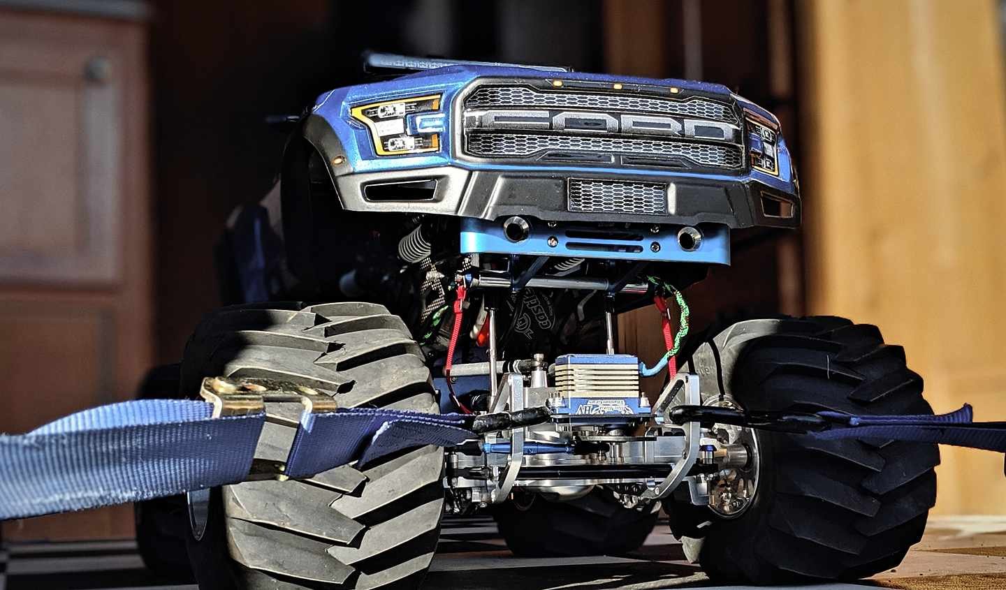 Front three-quarter view of the blue Ford Raptor RC body over its rebuilt chassis, aluminum shock towers and carbon fiber links visible.