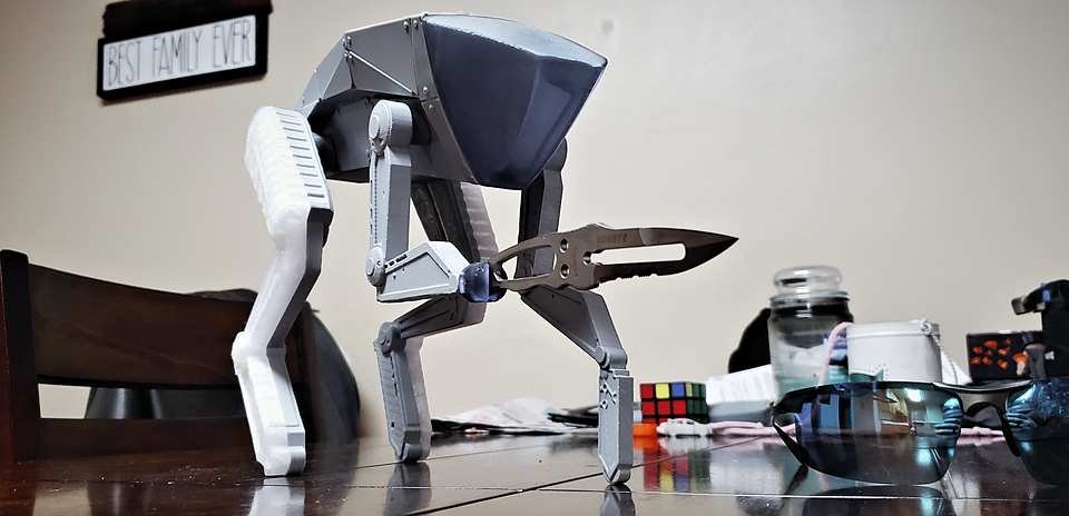 1:1-scale AT-ST-style walker leg assembly standing upright on a wood chair for a size check.